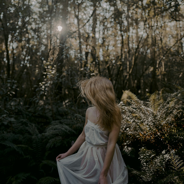 woman in white dress sitting on green grass during daytime