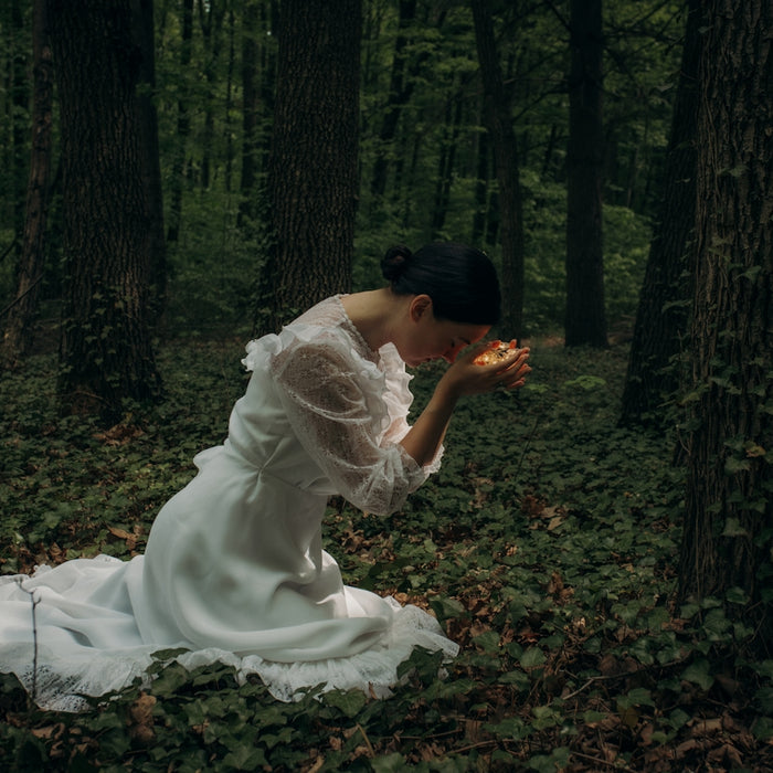 a man in a white dress sitting in a forest
