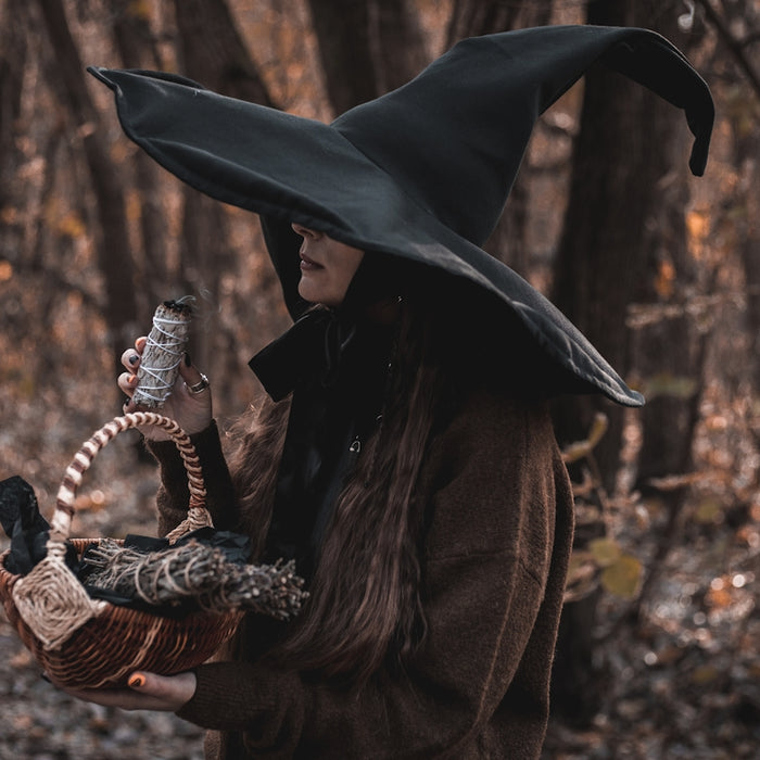 a woman wearing a witches hat holding a basket