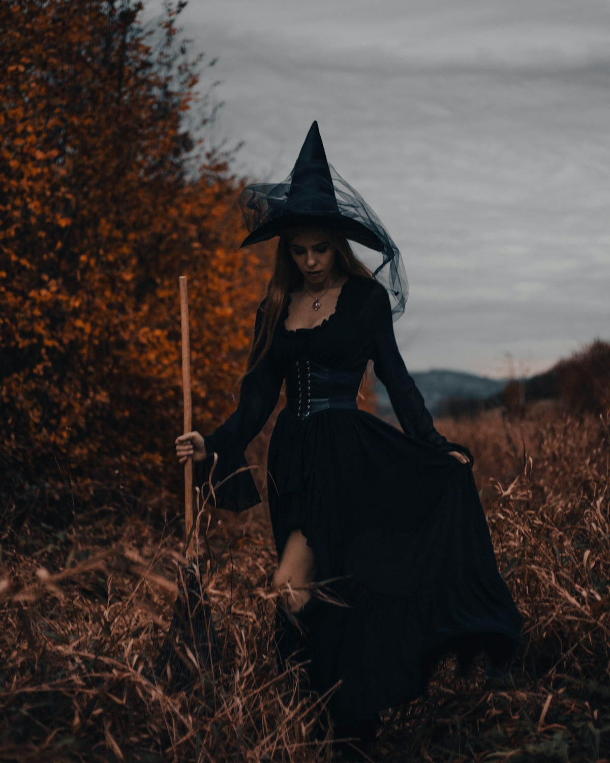 a woman in a witch costume walking through a field