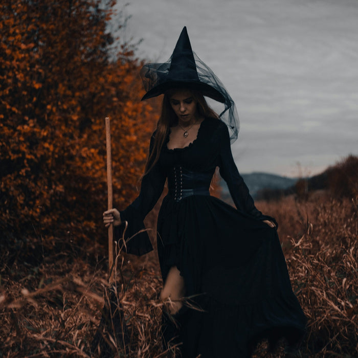 a woman in a witch costume walking through a field