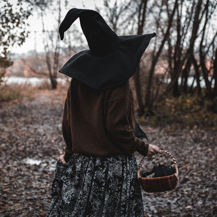 a woman wearing a witches hat and holding a basket