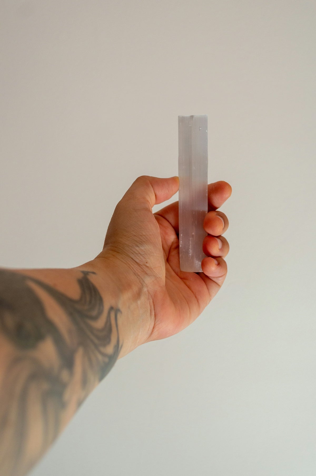 Hand holding a translucent crystal against a white background