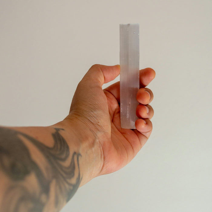 Hand holding a translucent crystal against a white background
