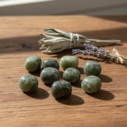 Green stones on a wooden surface with lavender in the background