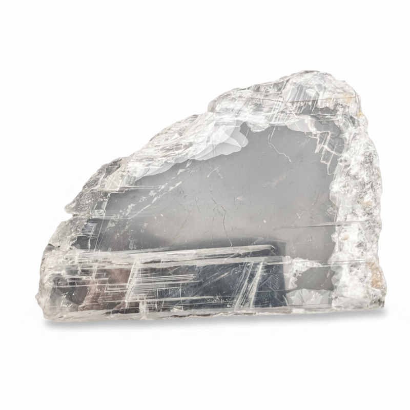 A raw, rough-cut clear selenite specimen showing layered tabular crystal structures and internal gray smoky areas, photographed on a clean white background.