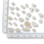 Collection of rough pink stones with a ruler for scale on a white background
