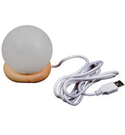 Small round Himalayan Salt lamp with wooden base and USB cable on a white background