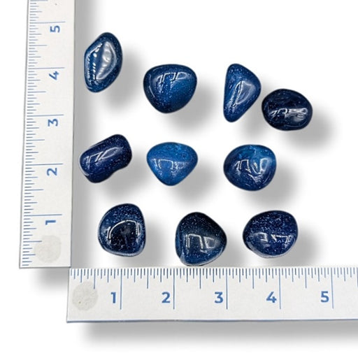 Blue stones on a white background with a ruler for scale