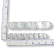 Two selenite wands next to a ruler on a white background