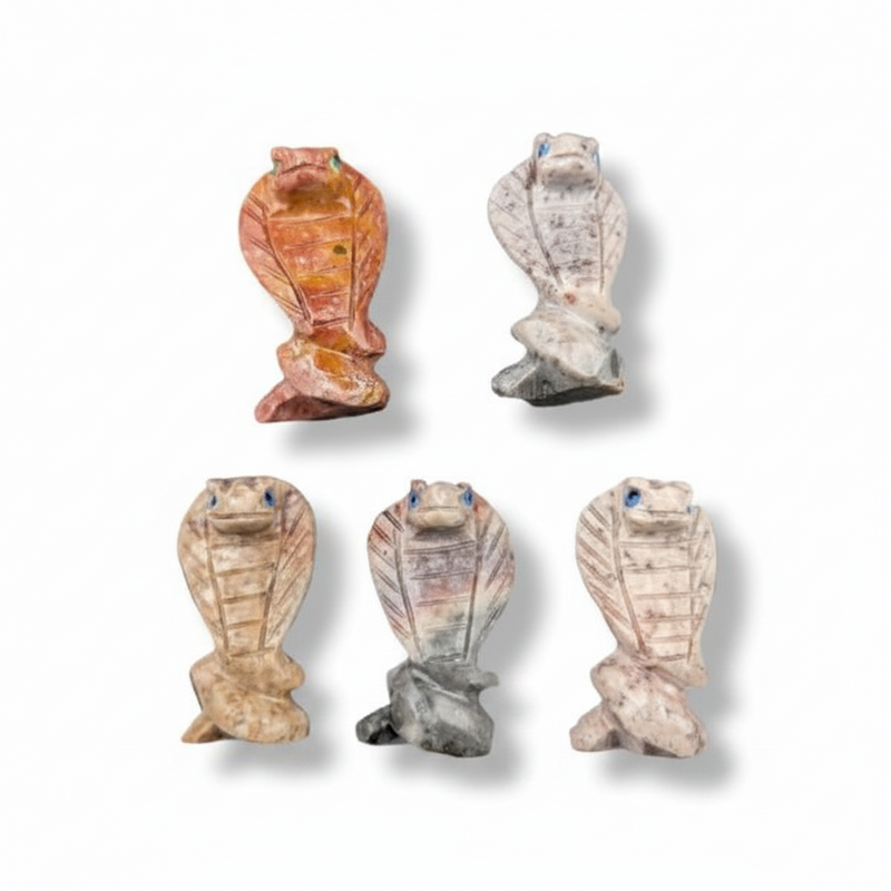 Five small carved cobra figurines in different stone-like colors, arranged on a plain white background with soft drop shadows.