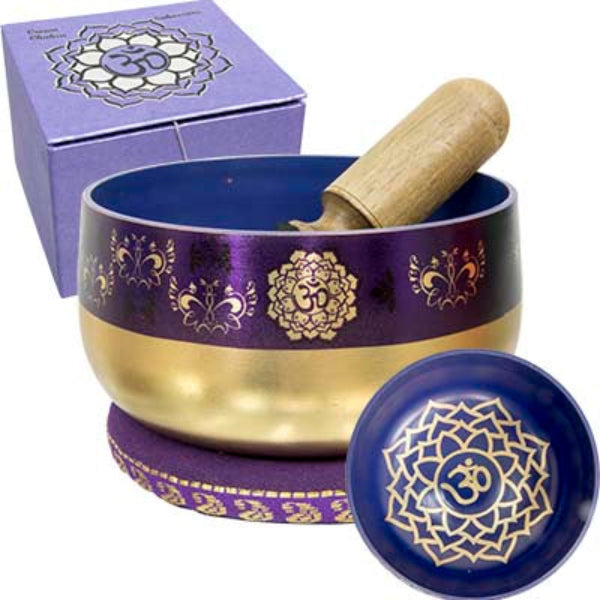 A purple and gold Tibetan singing bowl set with a wooden mallet, shown with its matching purple box and lid on a white background.