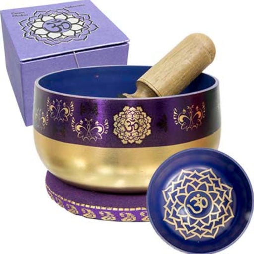 A purple and gold Tibetan singing bowl set with a wooden mallet, shown with its matching purple box and lid on a white background.