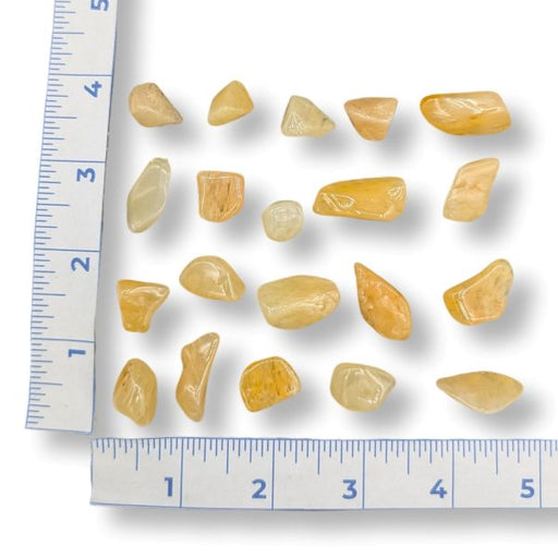 Set of yellow stones next to a ruler for size reference on a white background