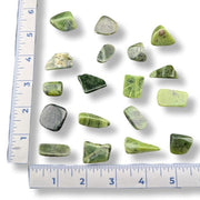 Green stones on a white background with a ruler for scale