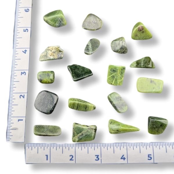 Green stones on a white background with a ruler for scale