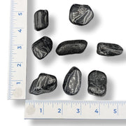 Black stones on a white background with a ruler for scale