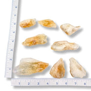 Set of raw citrine points with a ruler for scale on a white background