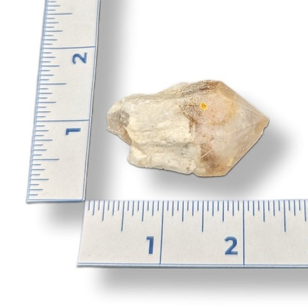 Raw crystal rock next to a ruler on a white background