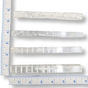 Set of crystal sticks with a ruler for scale on a white background