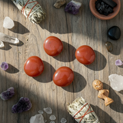 Red stones on a wooden surface with crystals and other items