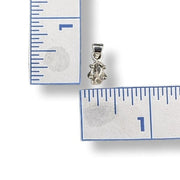 Silver pendant next to a ruler on a white background
