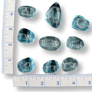 Blue gemstones on a white surface with a ruler for scale.
