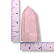 Pink crystal tower next to a ruler on a white background