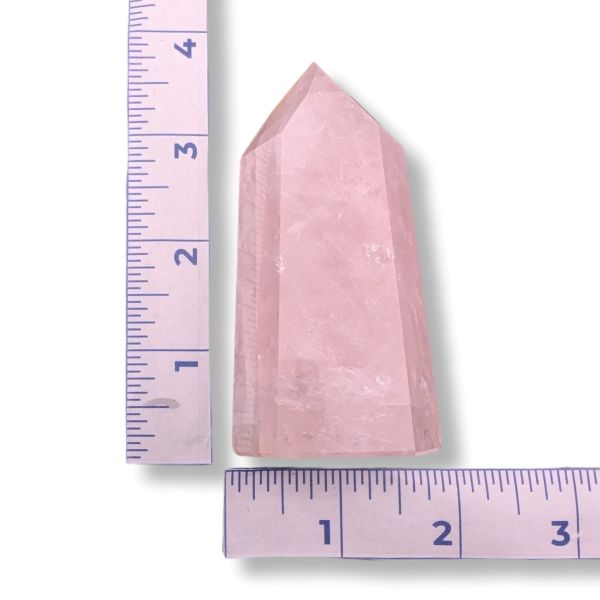 Pink crystal tower next to a ruler on a white background