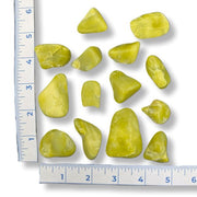 Set of green stones with a ruler for scale on a white background