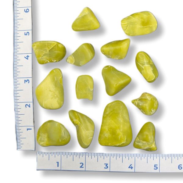Set of green stones with a ruler for scale on a white background