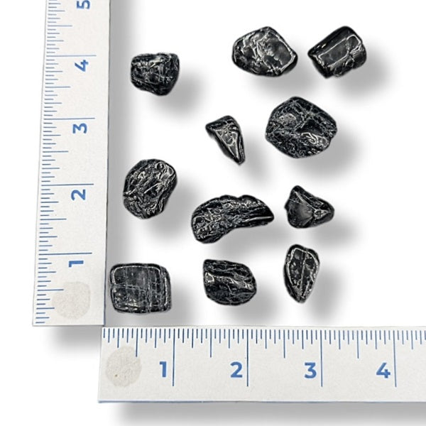 Black stones on a white background with rulers for scale