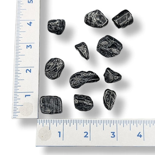 Black stones on a white background with rulers for scale
