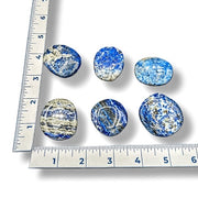Blue and white marbled stones with a ruler for scale on a white background