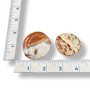 Two marbled stones next to a ruler on a white background