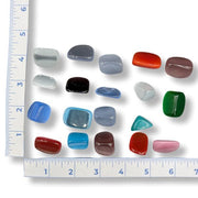 Assorted colored stones with a ruler for scale on a white background