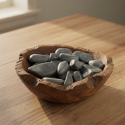 Black jade tumbled in a wooden bowl on a kitchen table