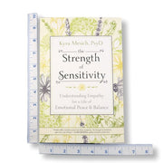 The book 'The Strength of Sensitivity' by Kyra Mesich, PsyD is displayed on a white background with a blue measuring tape on the left and a blue measuring tape below to show its dimensions.