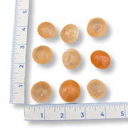 Orange spherical stones on a white background with a ruler for scale.