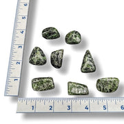 Green stones with a ruler for scale on a white background