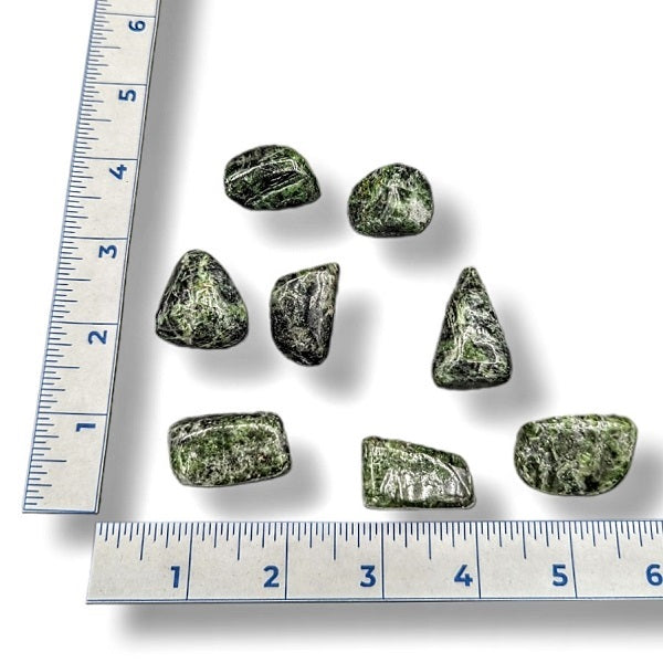 Green stones with a ruler for scale on a white background