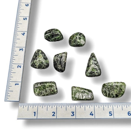Green stones with a ruler for scale on a white background