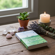Book titled 'Sacred Signs & Symbols' on a wooden table with crystals, a candle, and a plant.