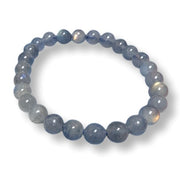 A beaded stretch bracelet made of smooth, polished round beads in a dusty slate blue color with subtle gray and light iridescent highlights, displayed on a clean white background.