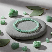 Green beaded bracelet on a stone with green stones and leaves around
