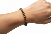 Hand wearing a beaded bracelet on a white background