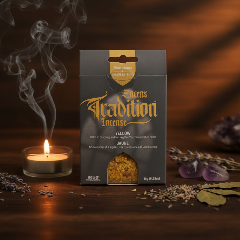 A package of Resin Tradition Incense Yellow is displayed on a dark wooden surface next to a lit candle with rising smoke, dried herbs, and purple crystals. The packaging is dark gray with gold lettering.