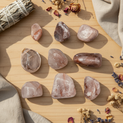 Hematoid quartz tumbled in a sunny setting with herbs, sage on a wooden table