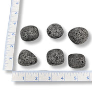 Black volcanic stones with a ruler for scale on a white background