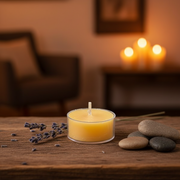 Candle on a wooden surface with lavender and stones, blurred background of candles and furniture.